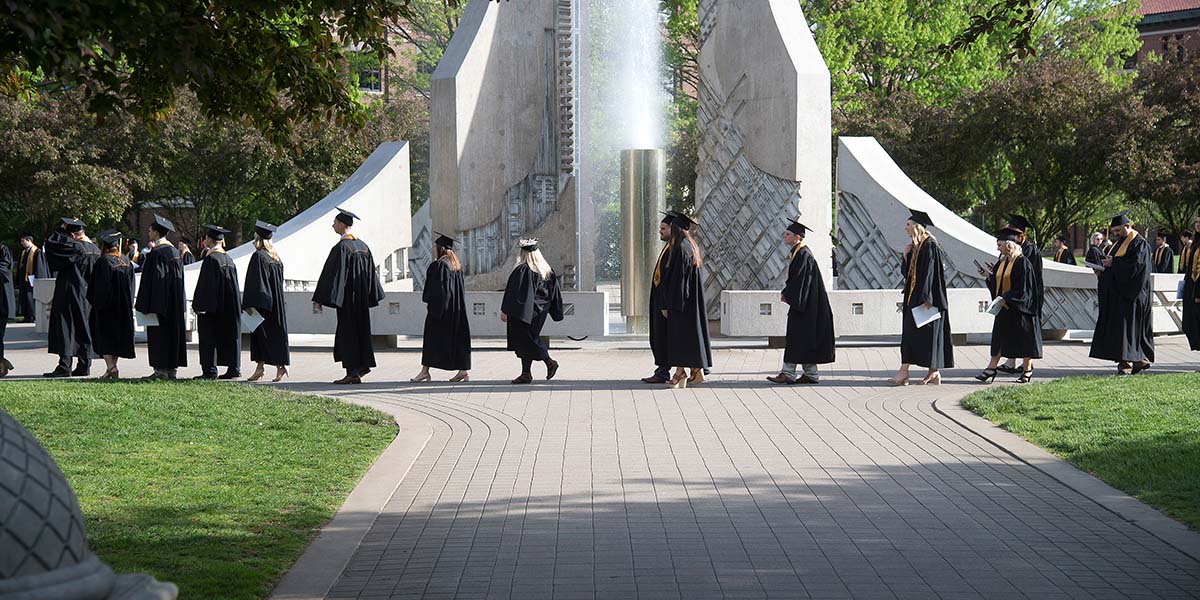 graduates walking n front of the engineering fountain