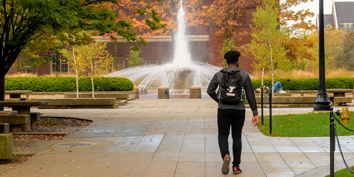 student walking by fountain
