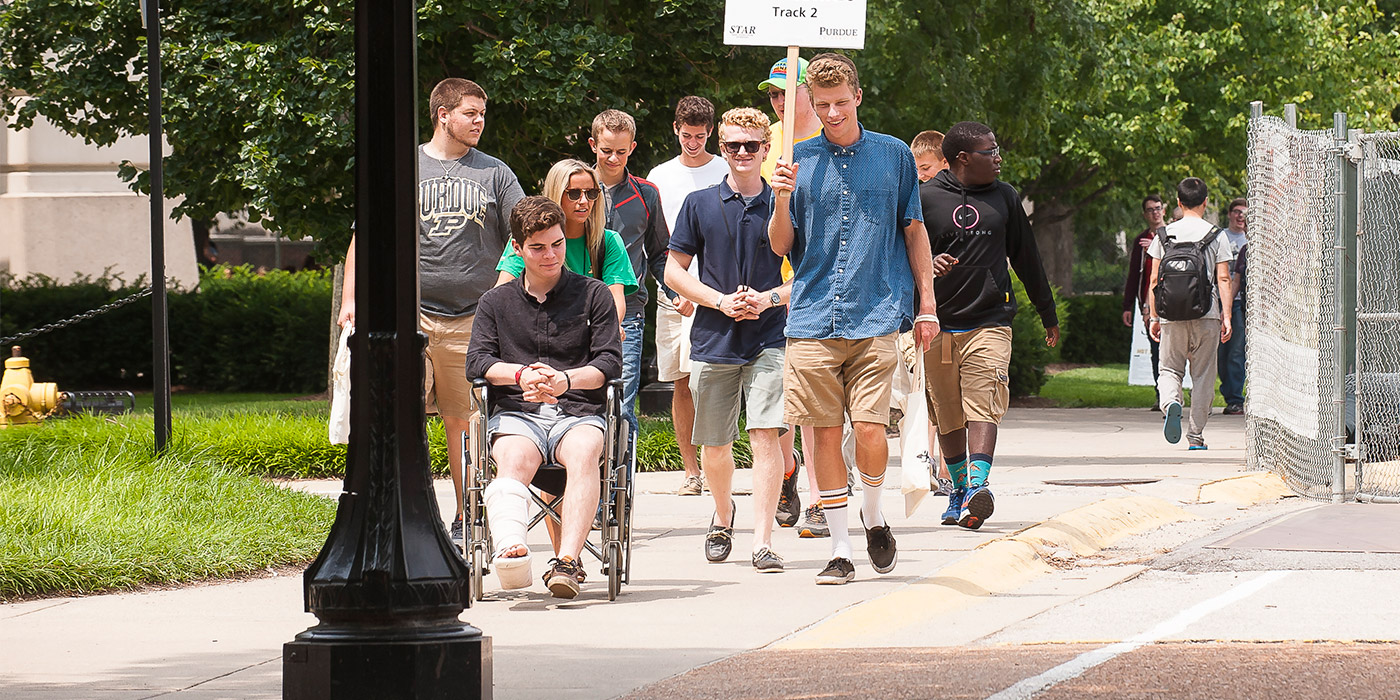 Pictured: students at Purdue's STAR orientation program walk down the sidewalk. One man is pushed in a wheelchair 