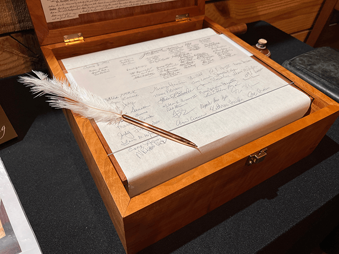 The open cherry wood display box with the signature scroll and replica quill pen