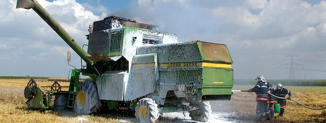 Photo of combine and firefighters spraying foam