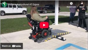Preview image of YouTube video showing young woman navigating powered wheelchair over temporary ramp in parking lot