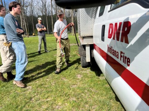 An instructor teaching a group of people about prescribed fire equipment.