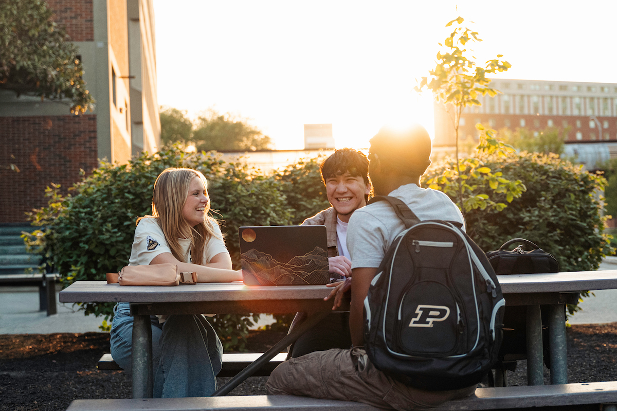 Student sitting at a table outside talking and laughing