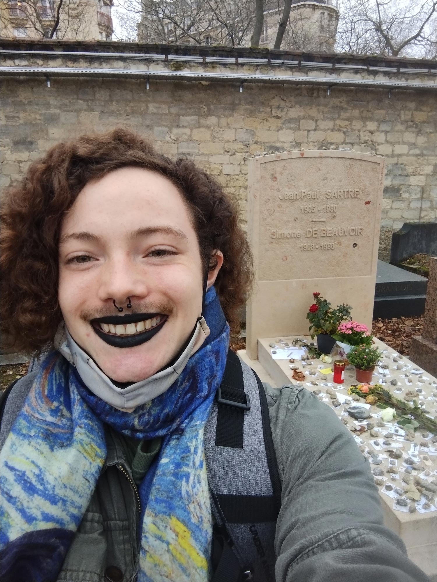Brian Boone, wearing a scarf, takes a selfie at a graveyard in Paris
