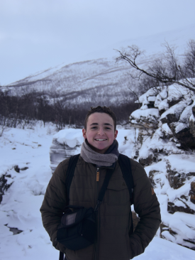 Nate Venckus dressed in winter gear smiles amid a scenic snowy backdrop