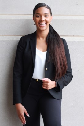Olivia West wears a black business suit and smiles for the camera