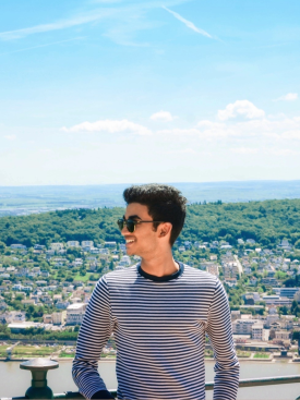 Viswamber Reddy Chandupatla wears sunglasses and looks sideways with a sunny city background behind him