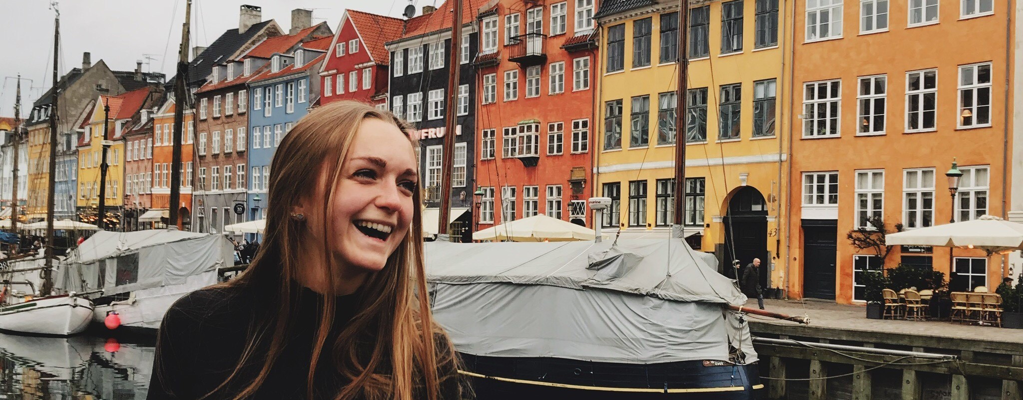 Girl smiling in front of colorful buildings.