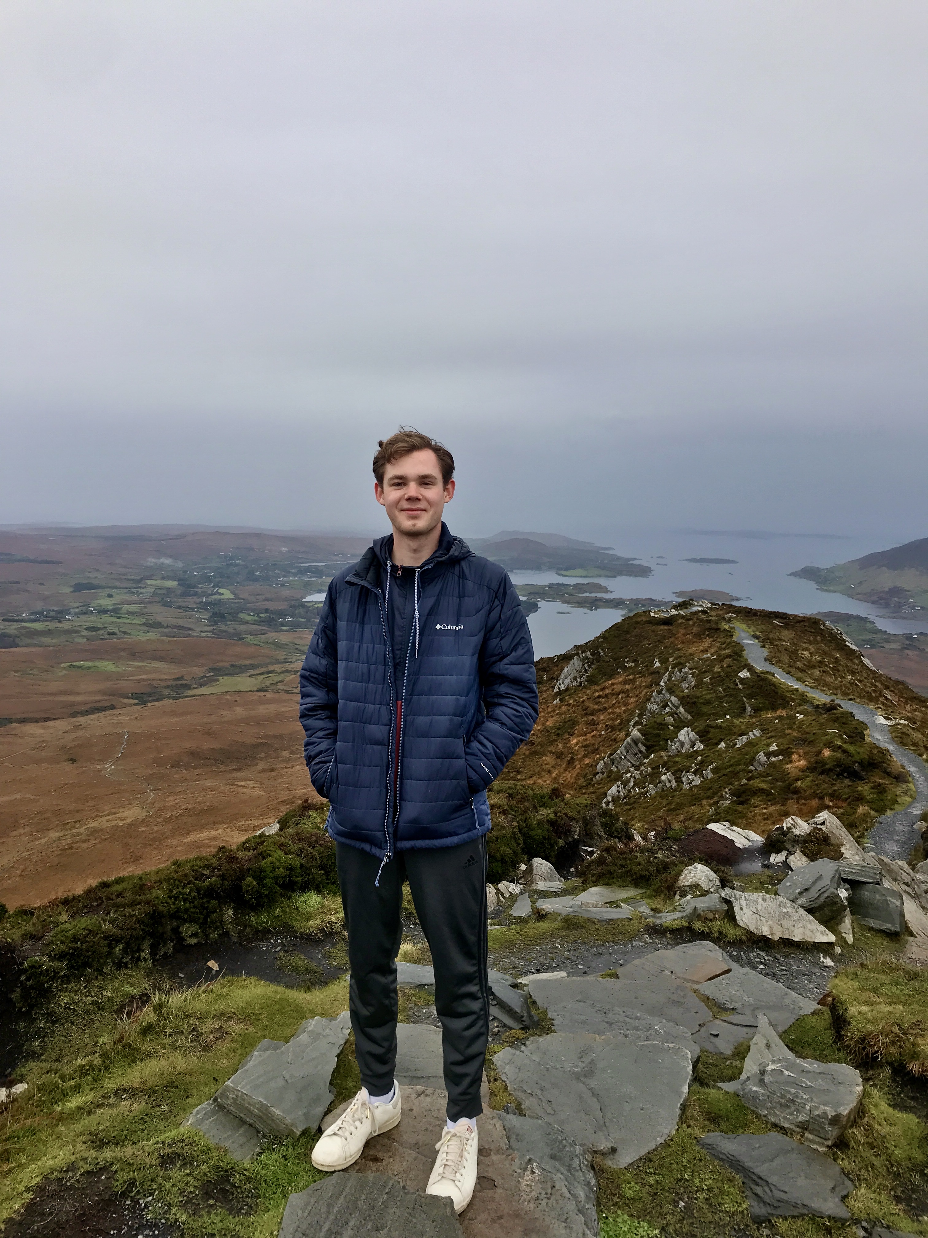 Ian Heinig stands on a rock along a rocky coastline amid misty weather