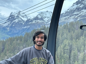 Mohammad Khokha poses while riding a cable car with mountains in the background
