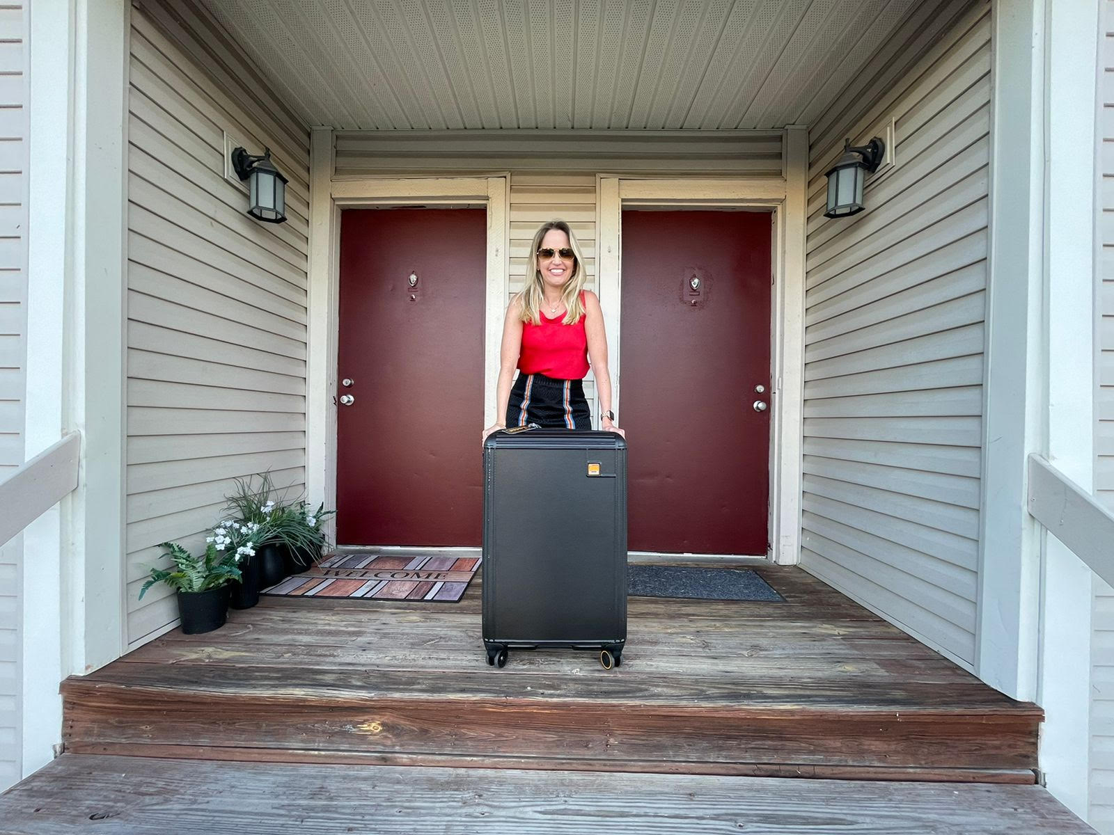  Juliana Pereira standing in front of red door with suitcases