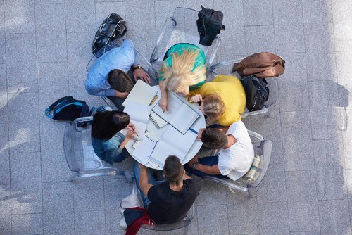 Six students studying outside while sitting around a round table