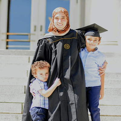 Ola Wasel in her graduation gown, standing with her two children