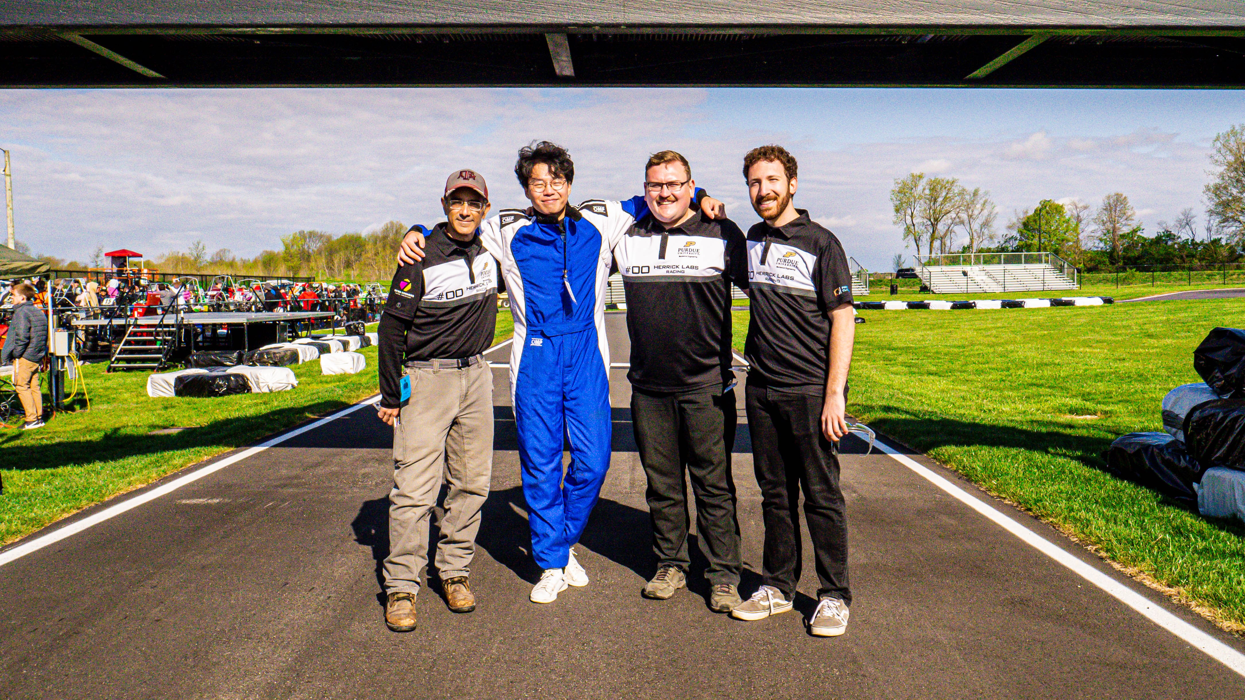 Four graduate students posing on the Purdue Grand Prix race track