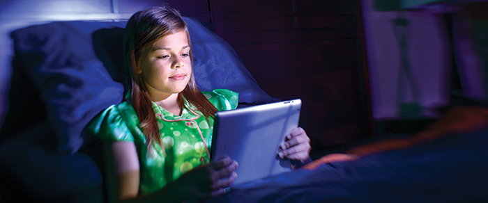 Little girl looking at iPad in bed