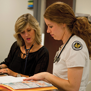 After seeing a pediatric patient at the Family Health Clinic of Carroll County nursing student Kelly Dyer consults with Jennifer Coddington