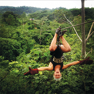 Emily Layman on a zipline over a forest canopy