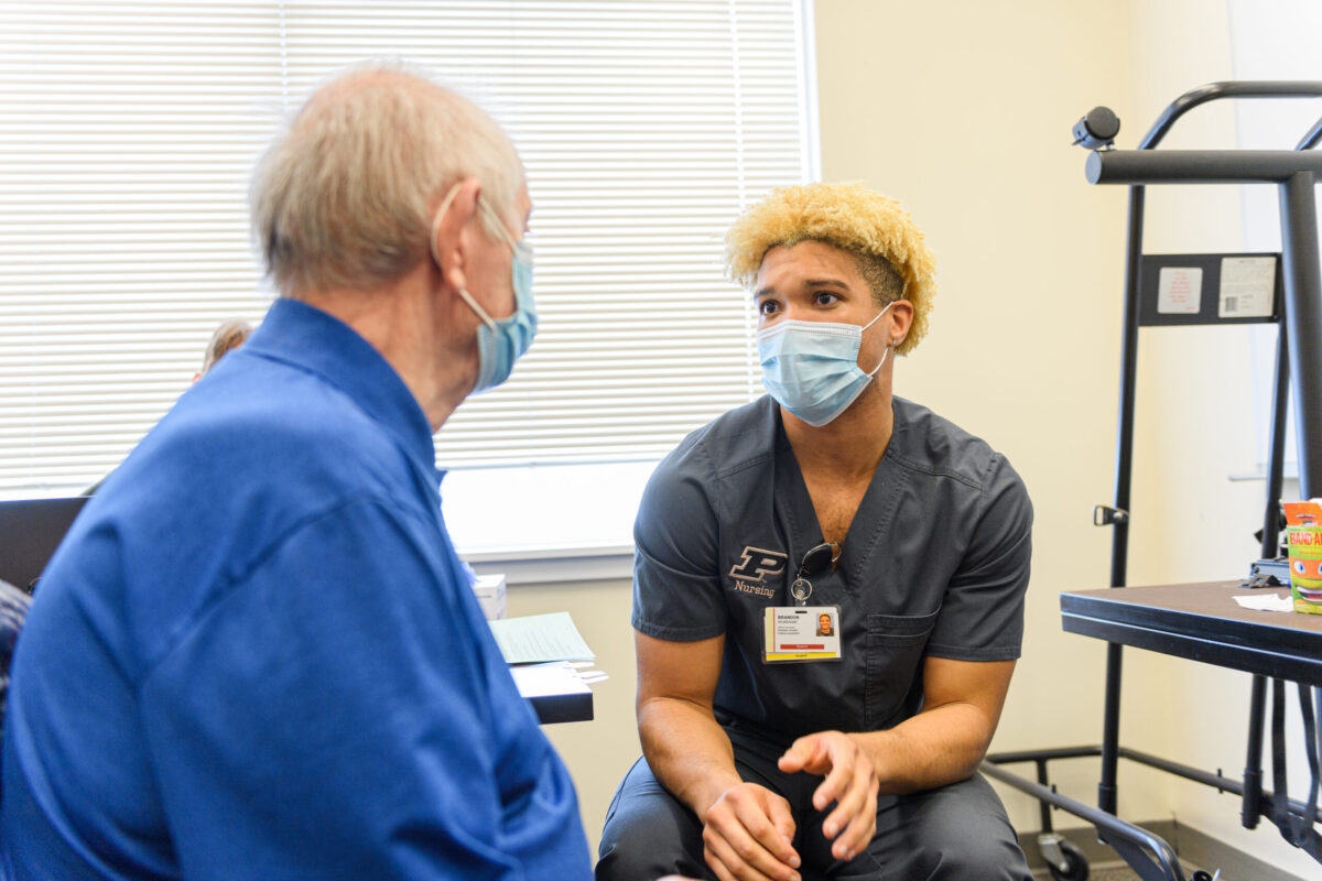 Brandon Sturdivant, then a Purdue University Nursing senior now a 2021 alumnus, discusses vital COVID-19 vaccine information with a patient last spring at a nursing clinic in Delphi.