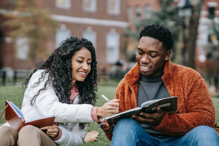 Two students sit on a lawn on campus