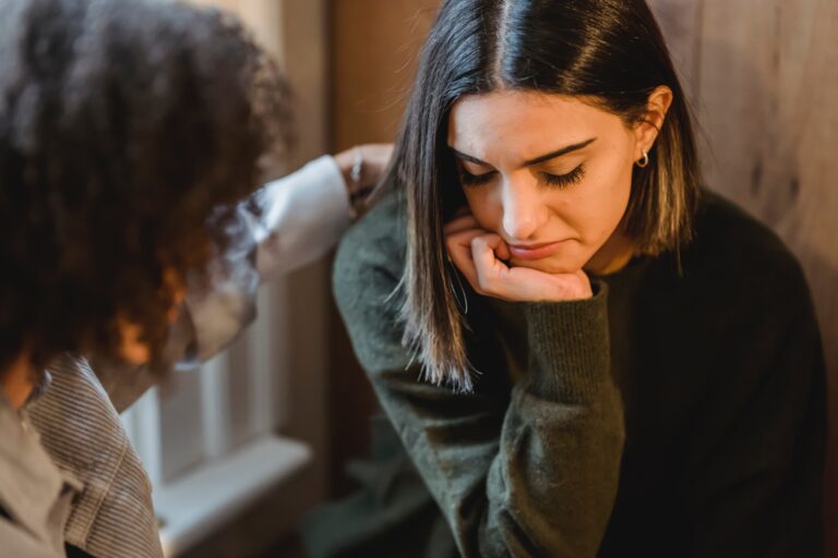 A girl looks sad while her friend comforts her