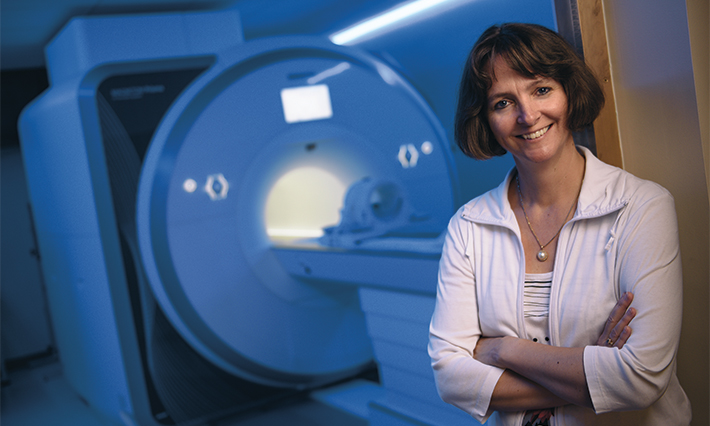Professor Ulrike Dydak stands in front of an MRI machine.
