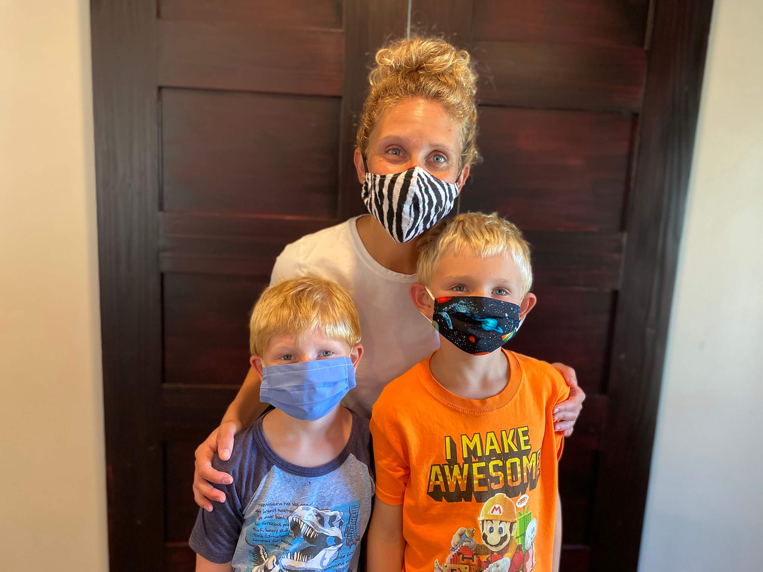 Meg Sorg poses behind two of her children wearing masks.