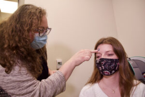 Arielle Borovsky applies a sticker to the forehead of lab assistant Rita Dietz.
