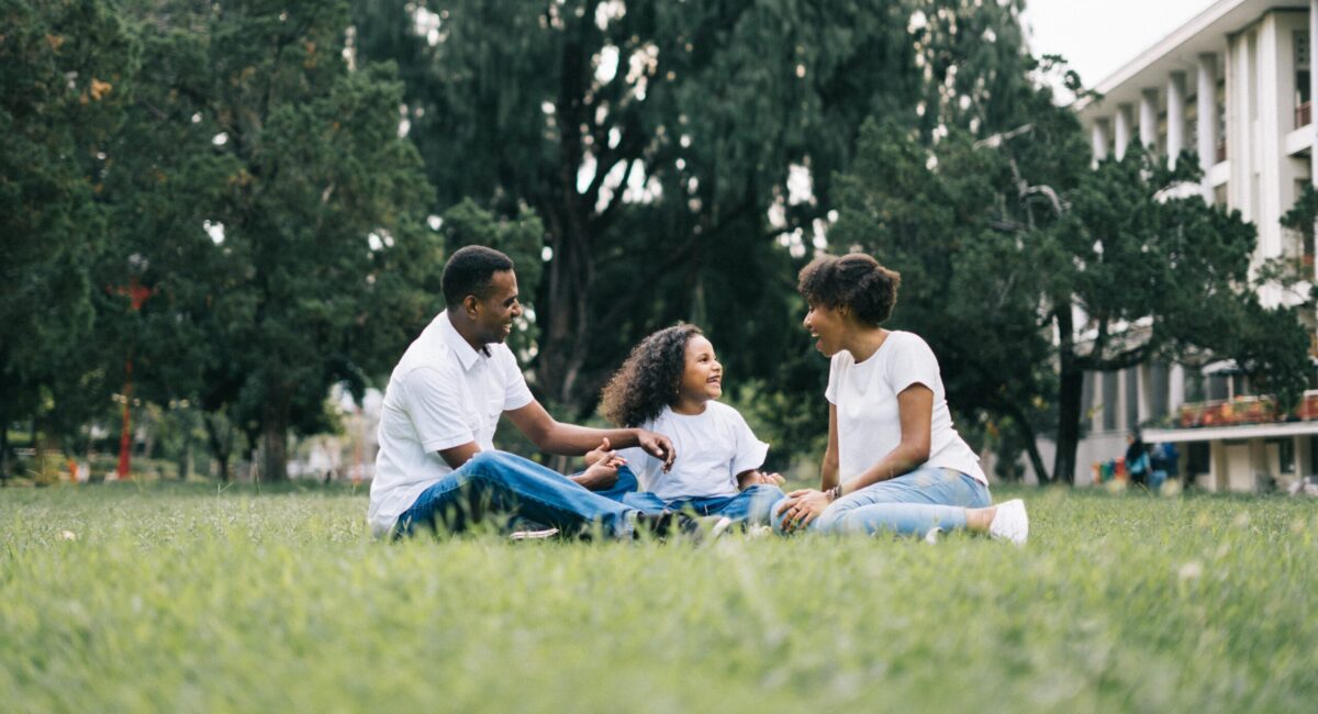 Smiling family sits together on grass