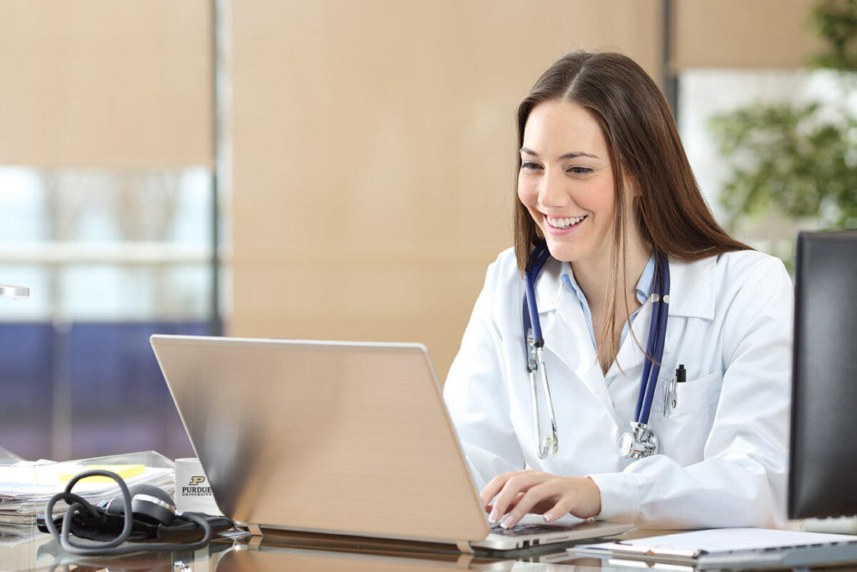 Smiling doctor uses laptop