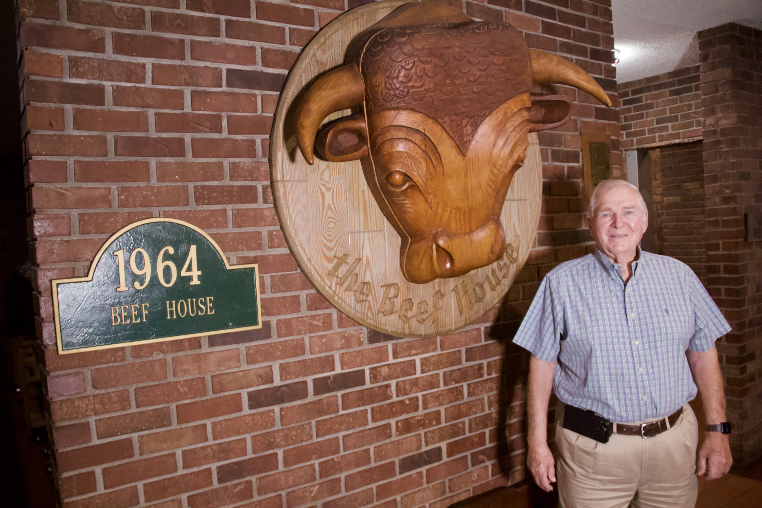 Robert Wright stands next to some Beef House signage in his restaurant's lobby.