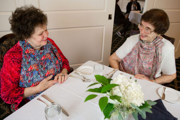 Two older women sit at a table wearing bonTops