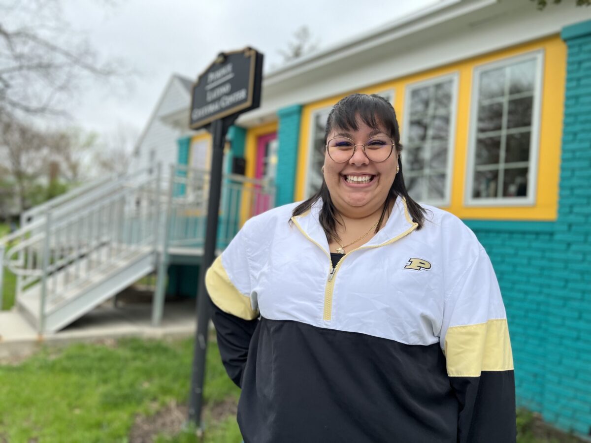 Jennifer Escobedo poses in front of the colorful Purdue Latino Cultural Center building.