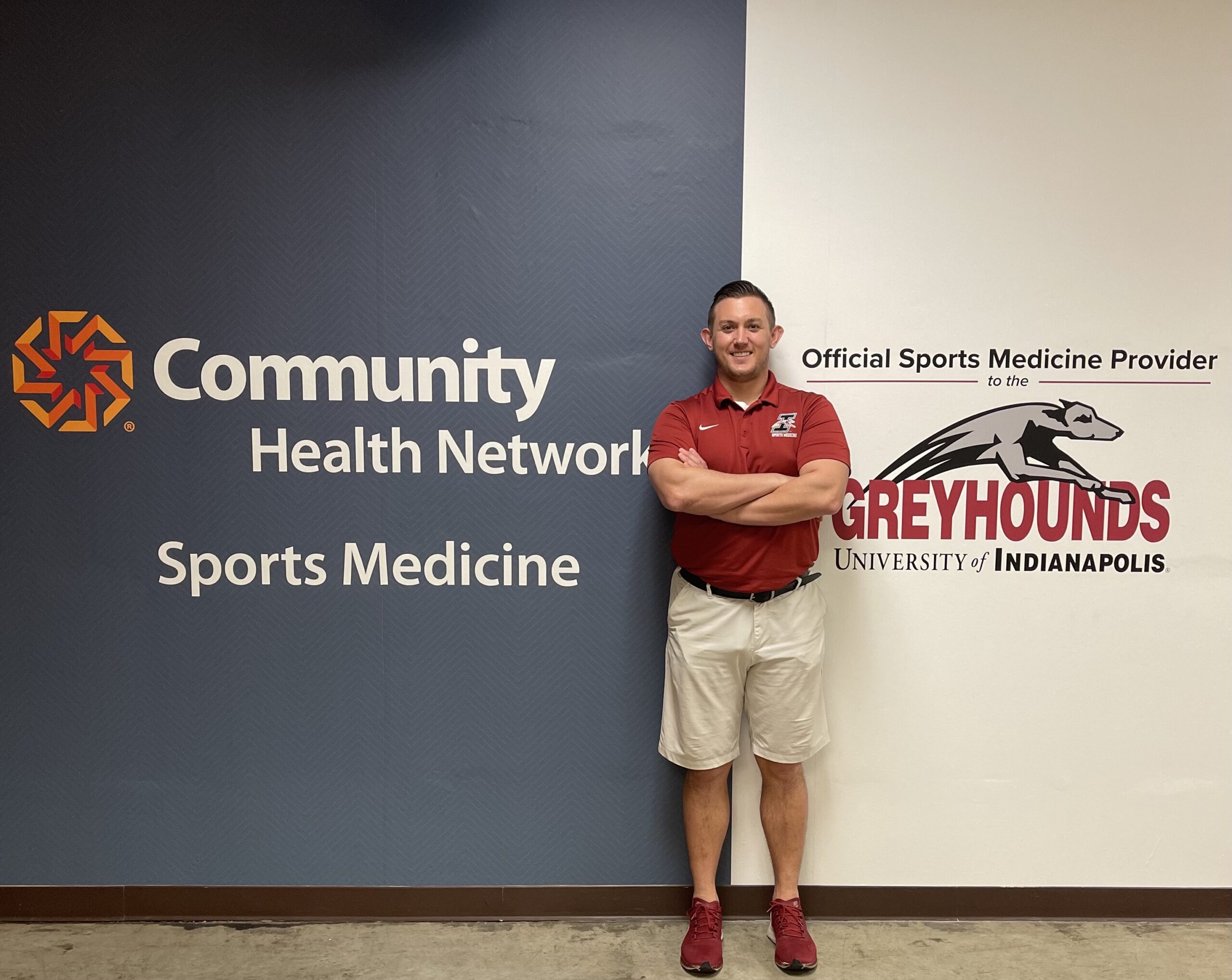 Devin Wyss stands in front of some signage at his job for Community Health Network.