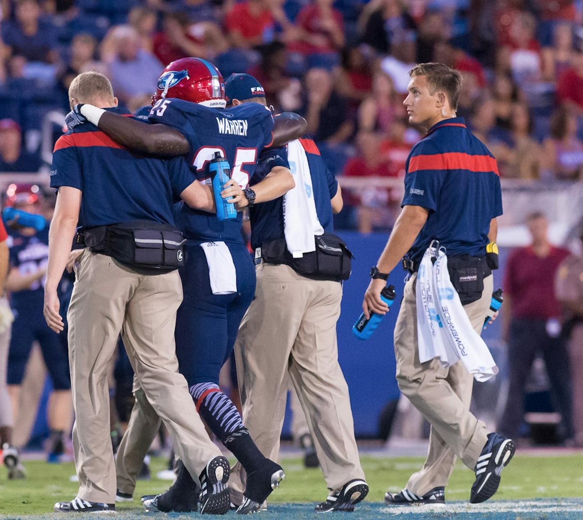 Devin Wyss and his fellow trainers help an injured player off the field.