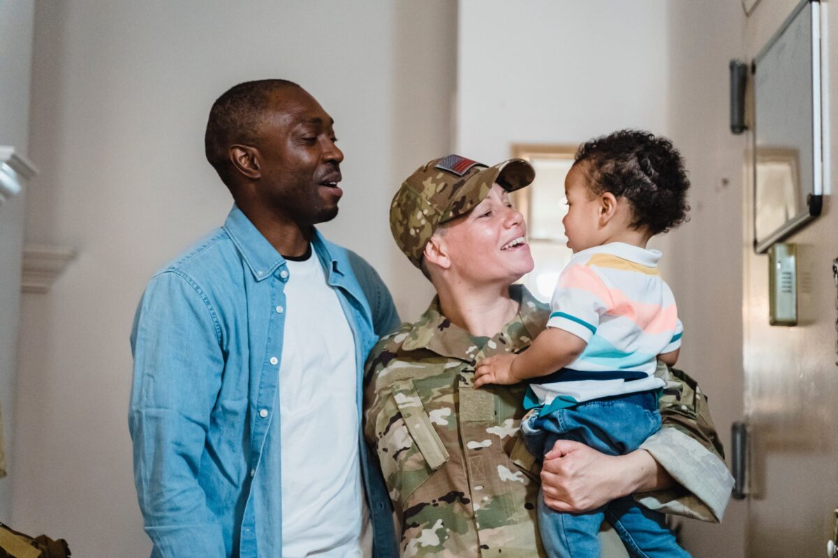 Military woman hugs husband and son