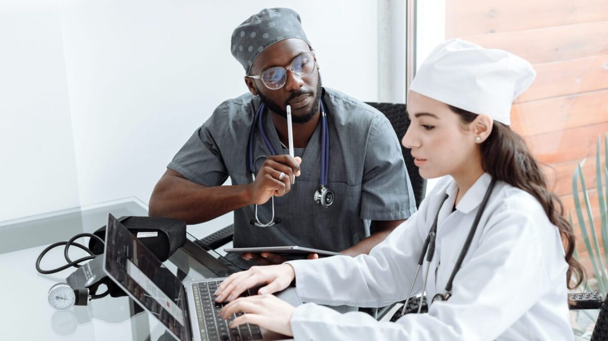 A nurse and physican talk while looking at a laptop