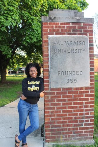 Liz Noland stands next to a column that reads "Valparaiso University, founded 1859."