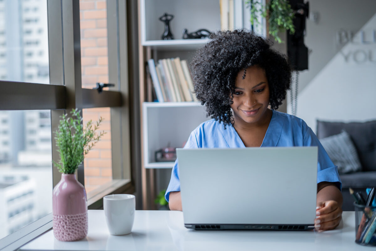 Woman in scrubs uses laptop