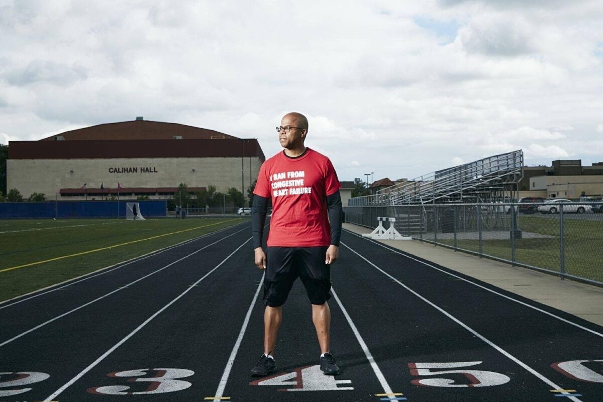 James Young II stands on a track wearing a shirt that says "I ran from congestive heart failure."