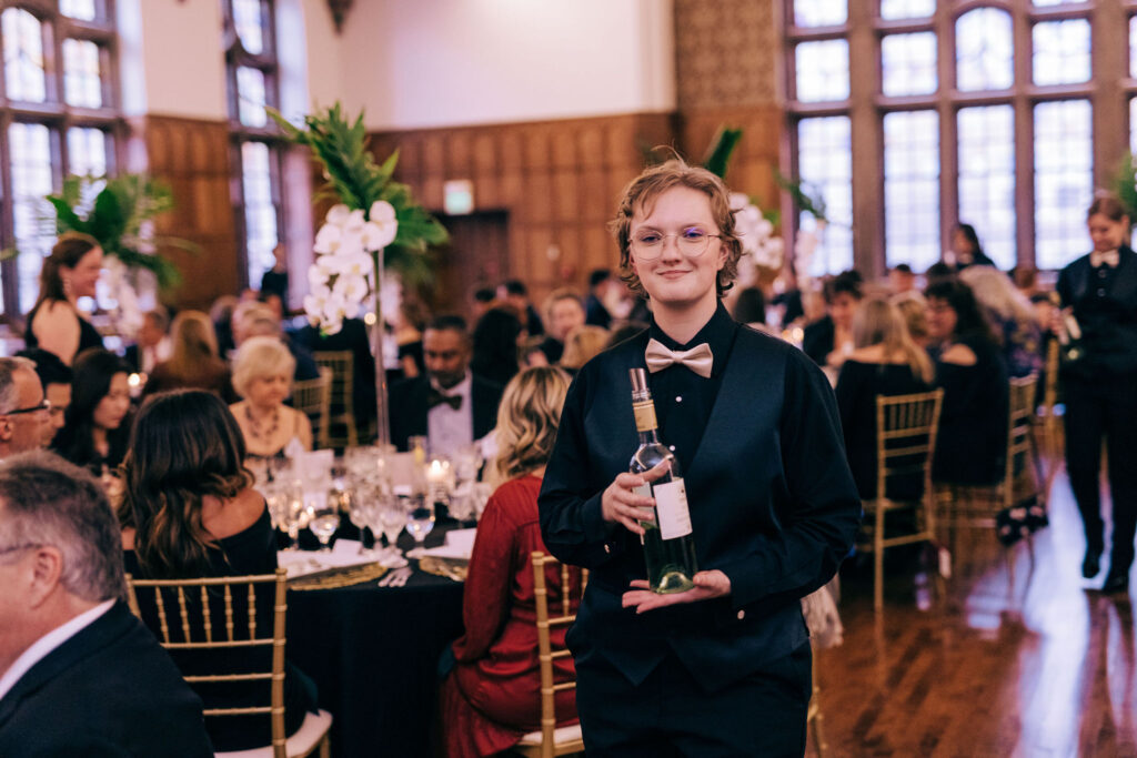 A student volunteer is ready to pour some wine.