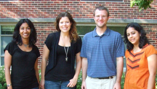 Erickson-DiRenzo stands with her advisor Preeti Sivasanker and two other colleagues in front of a brick building on campus.