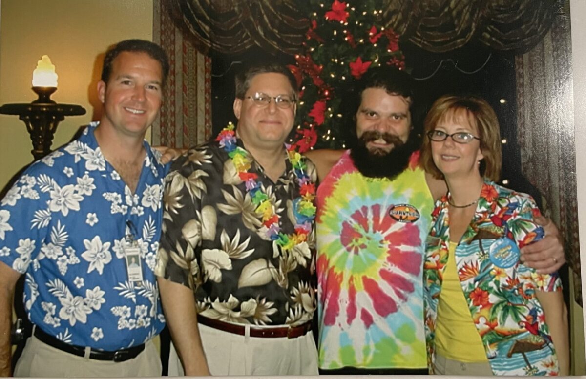 Dora poses with individuals all wearing Hawaiian shirts