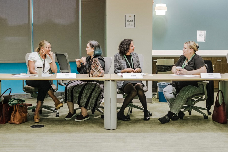 Women gather at a long table and talk