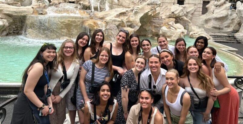 Students gather around Trevi Fountain to pose for a photo