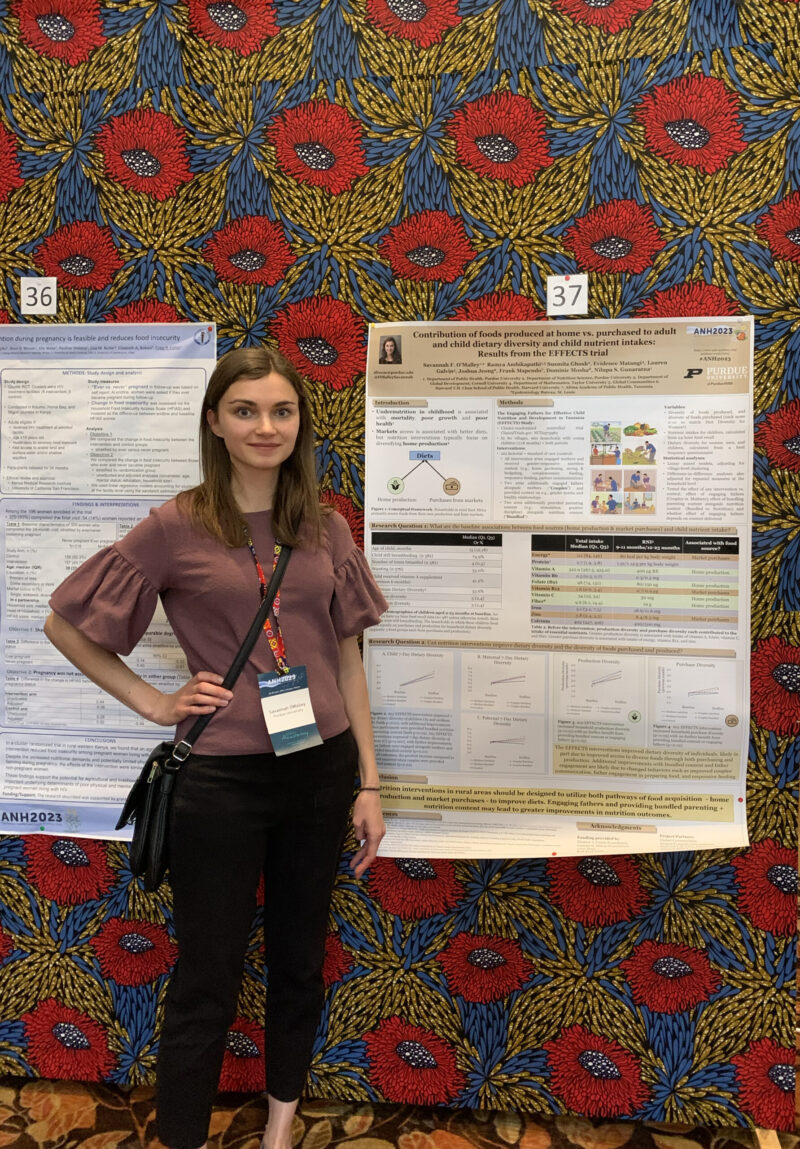 Savannah O'Malley stands in front of her research poster at a conference in Malawi.
