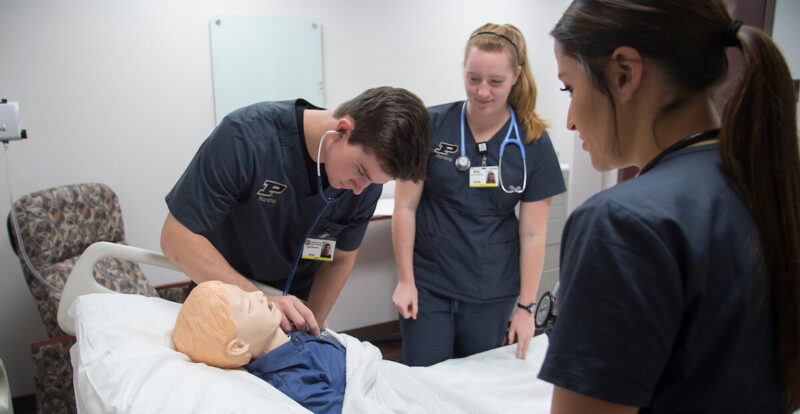 Three nursing students gather around a manikin in the Center for Nursing Education and Simulation