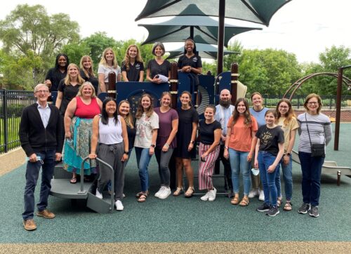 A large group of people pose for a photo in a playground area