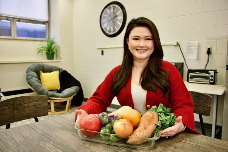 Julia Choi holds healthy Thanksgiving meal ingredients at a table.