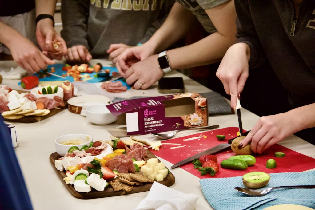 Students chop ingredients and assemble charcuterie boards in a class.